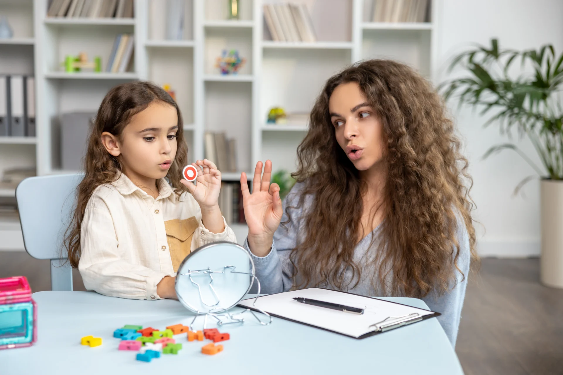 GettyImages-2165510202 A woman and girl sitting at a table with a clock.